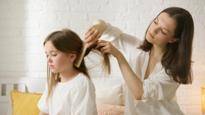 Parent carefully checking child hair for lice eggs with a fine-tooth comb