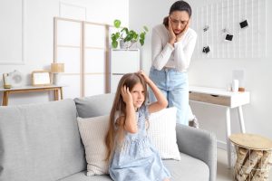 Worried mother comforting her daughter who is scratching her itchy scalp