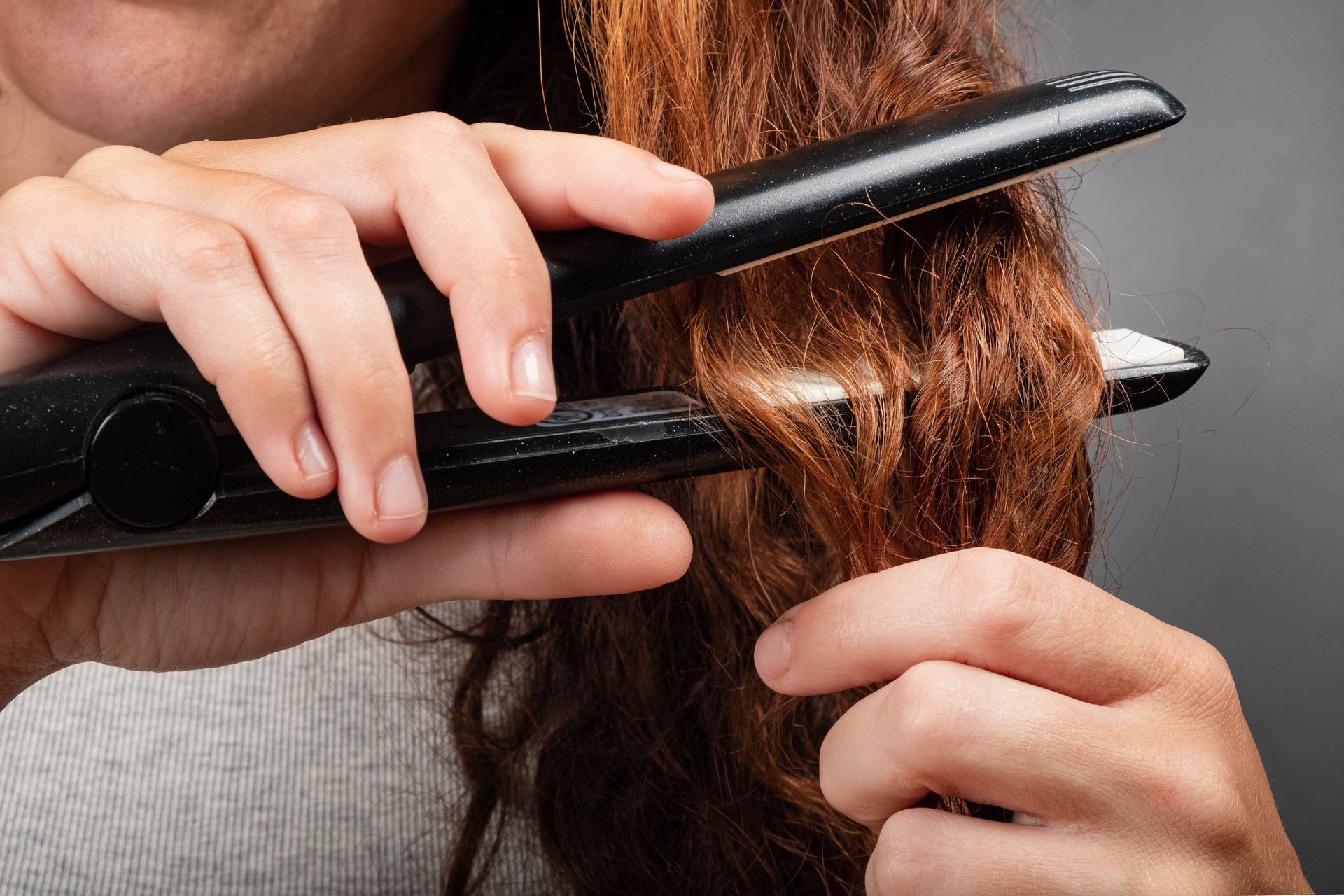 Close-up of a flat iron clamping a mid-length section of long hair